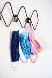 Blue and pink patterned PPE masks hanging on coat rack by door
