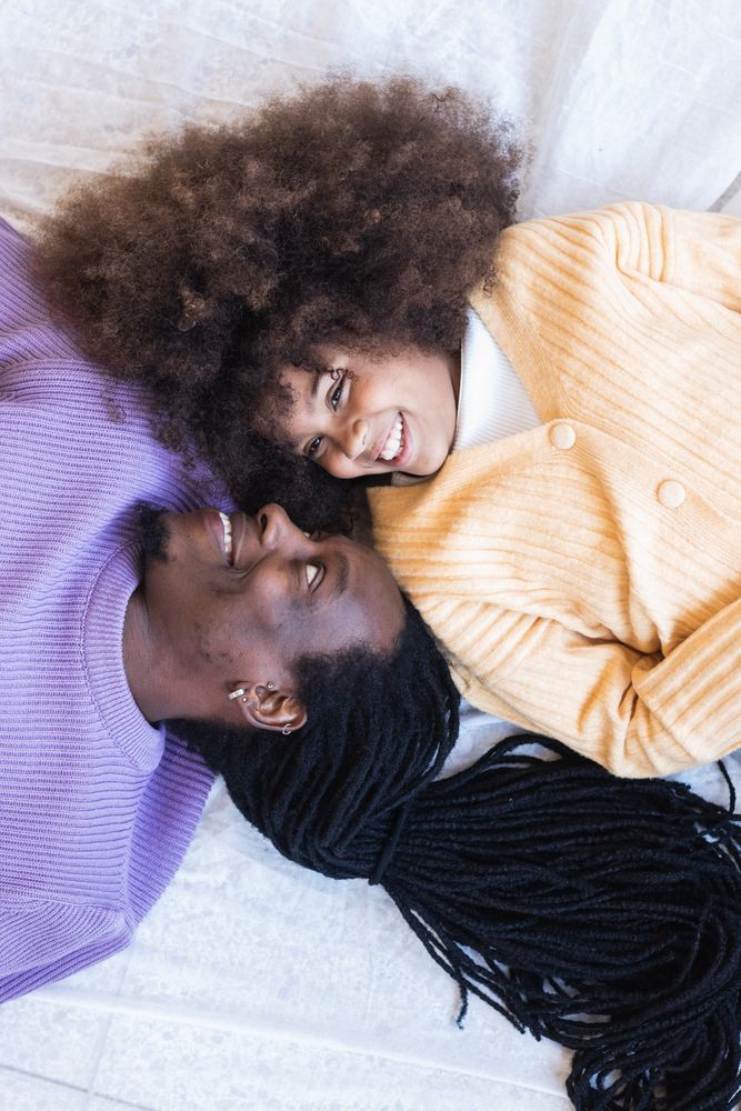 Happy Black girl lying with father on bed
