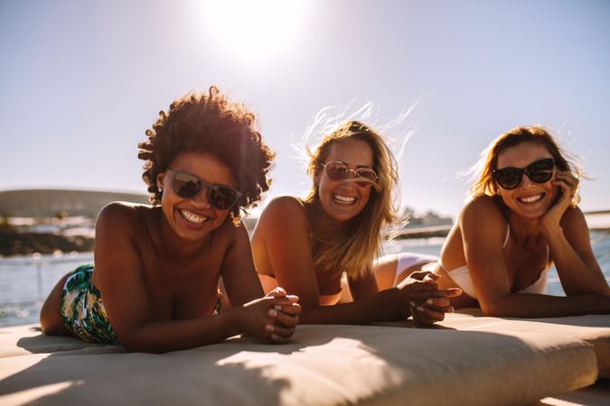 Group of beautiful women lying on stomachs and smiling at camera