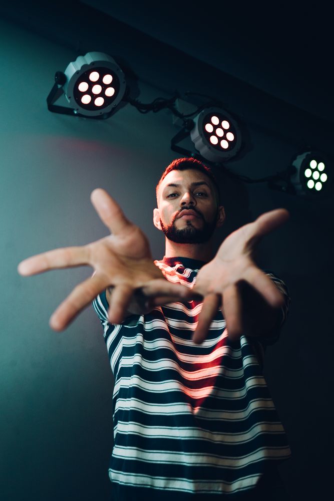 Man dancing in spotlight outstretching hand forward