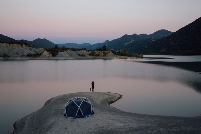 Man and dog with tent set up in the middle of nature