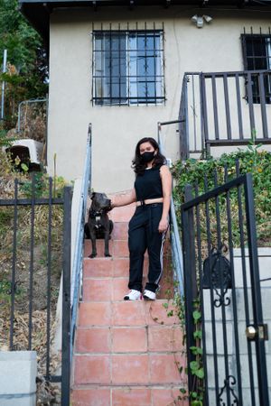 Woman standing on outside stairs with dog preparing to go for a walk