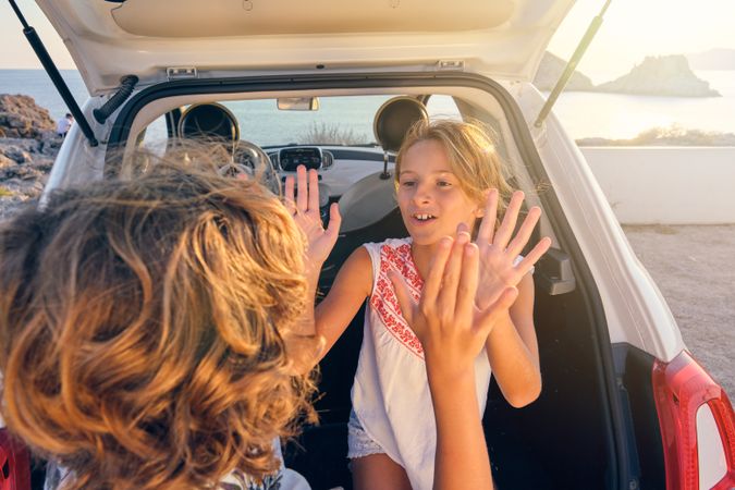 Cheerful kids having fun near car on seashore