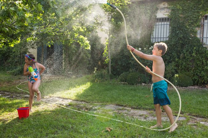 Little kids in swimwear having fun with splashing water