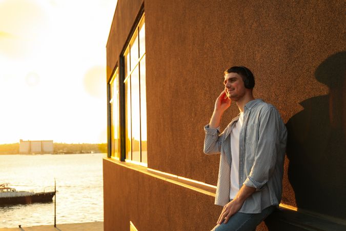 Young man in headphones listen music. Amazing sunset