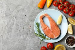 Composition with salmon meat and ingredients on gray background, top view
