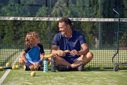 Cheerful coach with boy sitting on court