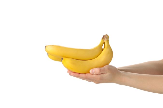 Female hands hold bananas, isolated on bright background