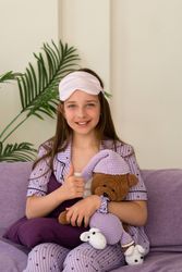 Girl smiling, giving thumbs up while sitting with teddy bear
