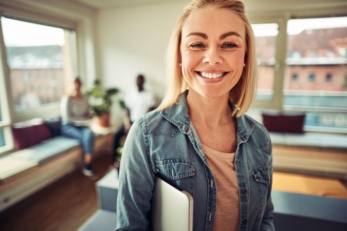 Portrait of happy blonde woman in a bright office