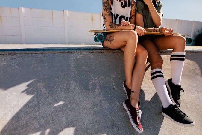 Cropped shot of women sitting on ramp after skateboarding