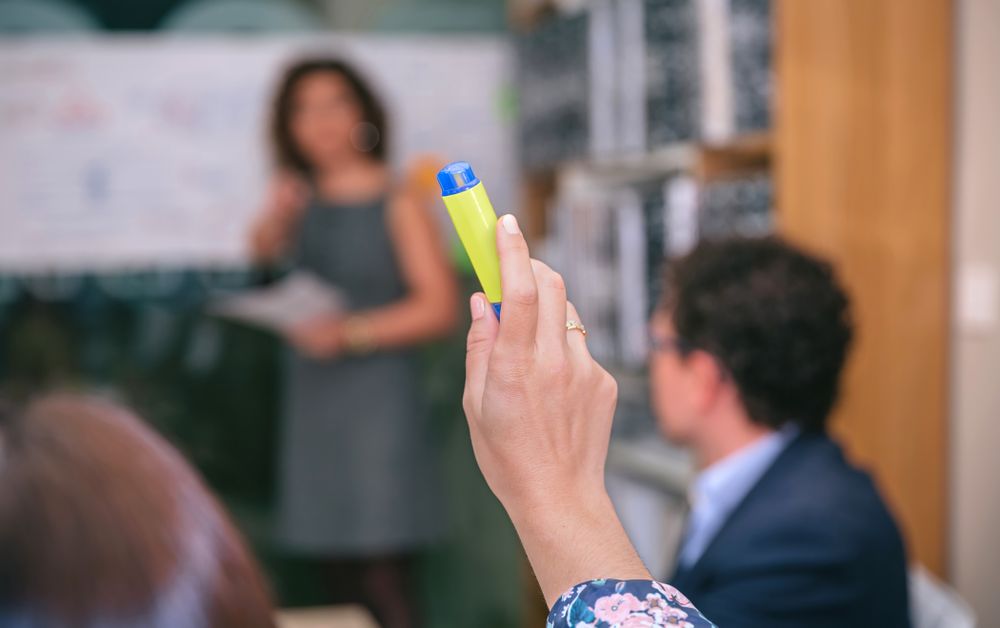 Business woman raising her hand to ask question in meeting