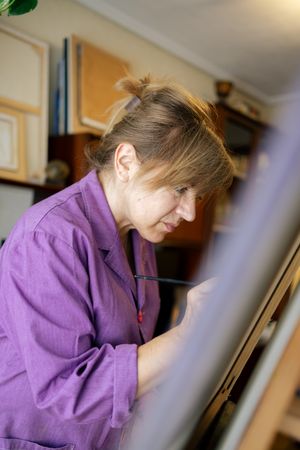 Adult woman painting canvas at home