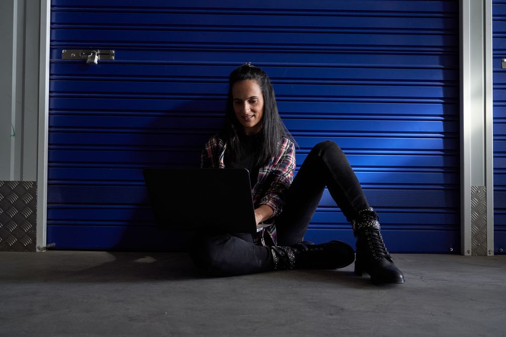 Positive woman browsing laptop near storage