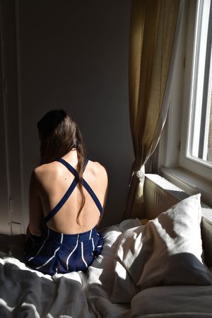 Back view of woman sitting on bed