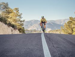 healthy man riding a bicycle on a mountain road in a sunny day