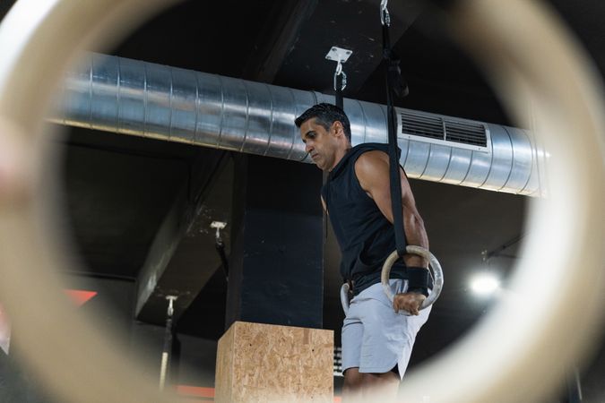 Hispanic sportsman exercising with gymnastic rings