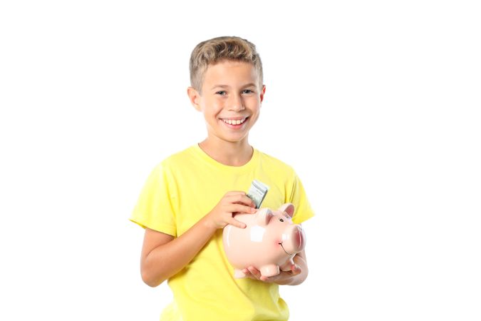 Boy in yellow t-shirt with piggy bank isolated on blank background