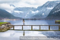 Woman standing on deck over peaceful alpine lake 5zpgAb