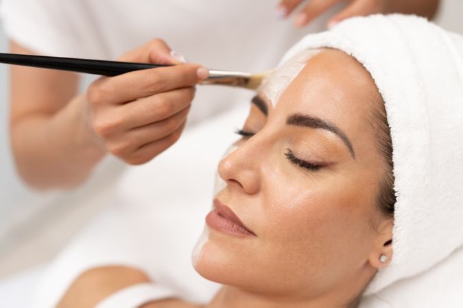Woman having a relaxing face mask professionally applied by beautician