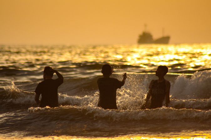 Silhouette of three boys at the beach during sunset