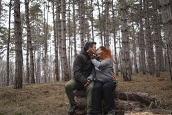 Emotional connection between a man and woman in a forest. Sharing a kiss on Valentines Day.