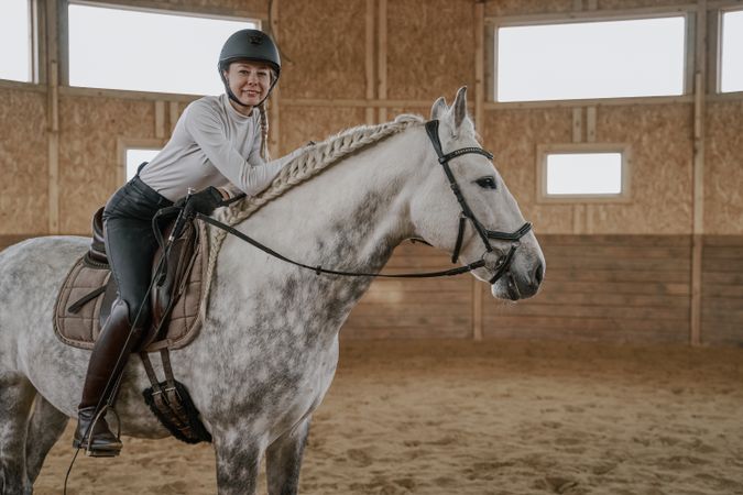 Rider riding dapple gray horse in round arena