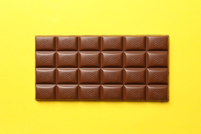Tasty chocolate bar on yellow background. Sweet food