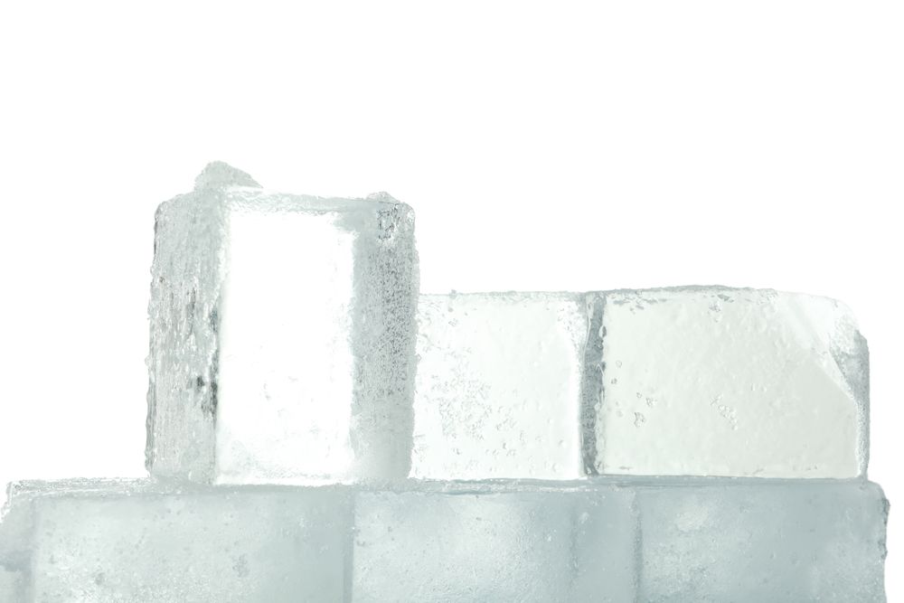 Close up of clear square ice cubes stacked in bright room
