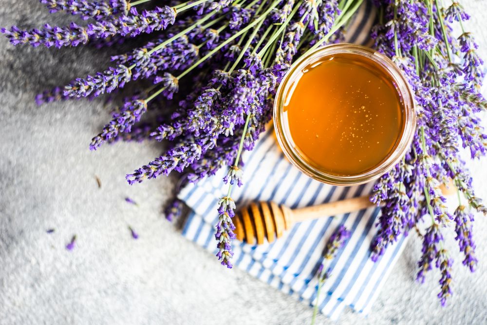 Top view of pot of honey with bunch of lavender with dipper and copy space