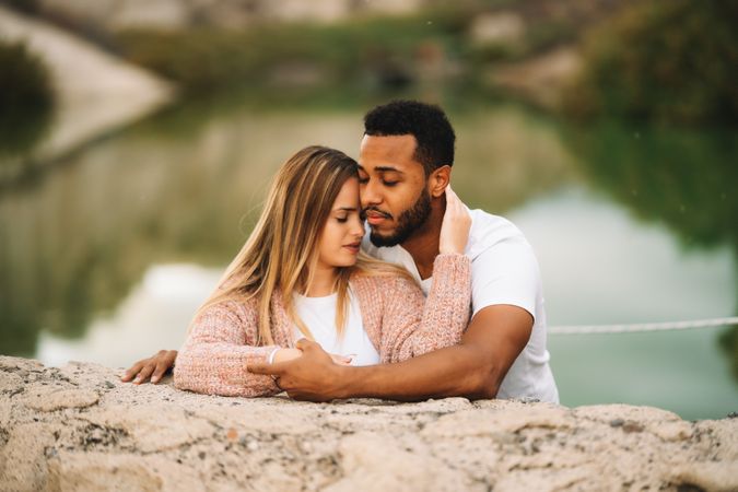 Happy multiethnic couple cuddling on nature