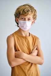Confident boy in medical mask with crossed arms