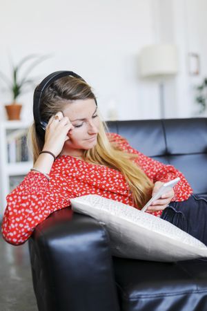 Woman relaxing listening to music wearing headphones and using a smartphone