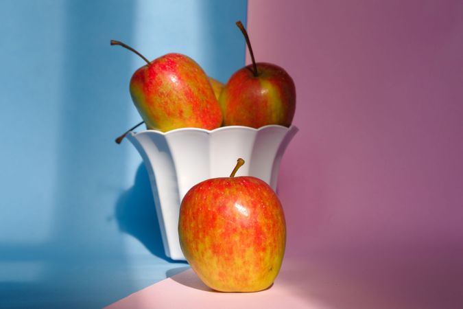 Photo of an apple in a container on a pink and blue background