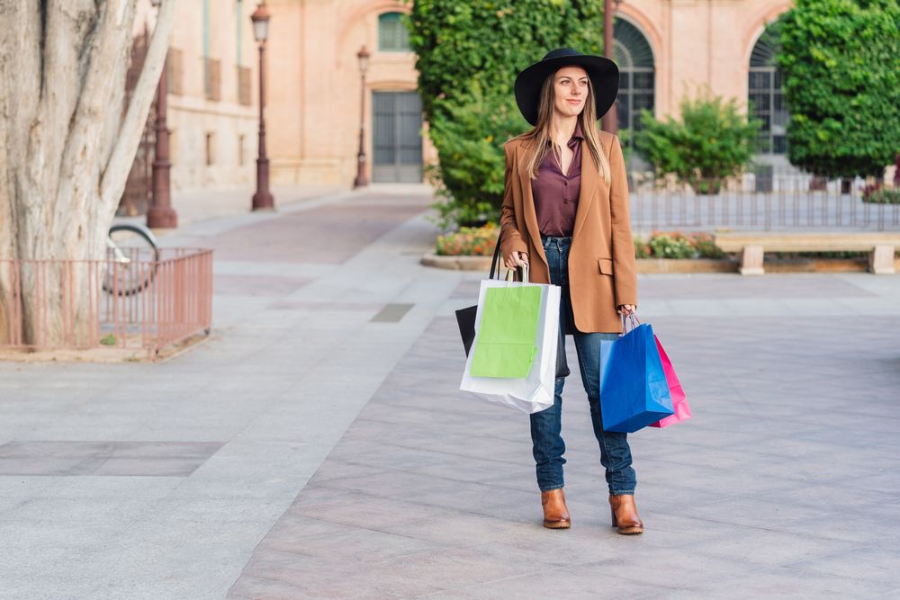 Content female in trendy wear doing shopping at city street