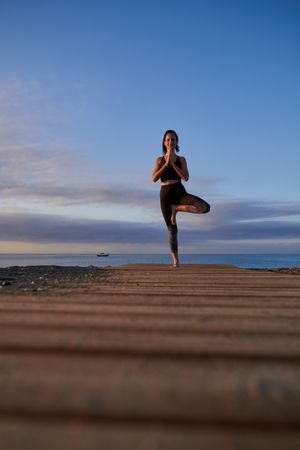 Woman practicing Tree pose on shore