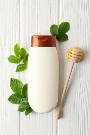 Natural hair care. Blank shampoo bottle and natural ingredients on wooden background