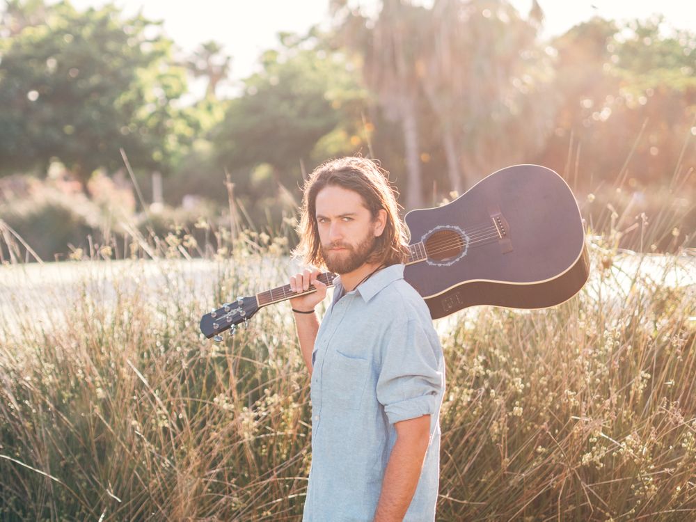 Hipster man in jungle with guitar
