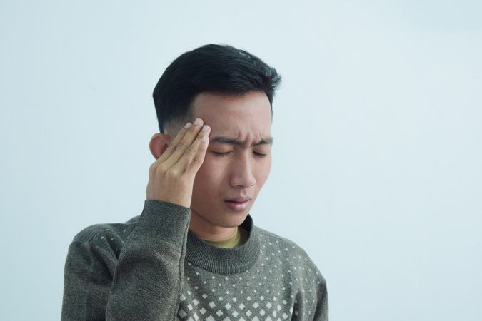 Asian young man touching head in pain