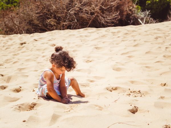Cute little girl playing with sand at beach