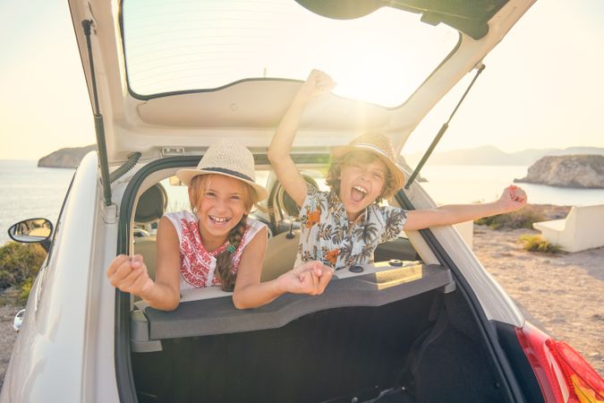 Children sticking their heads out of the trunk of a car doing ge