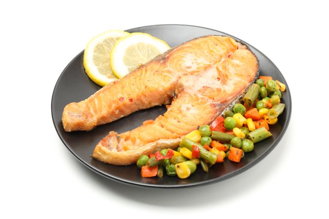 Plate with grilled salmon and vegetables isolated on blank background
