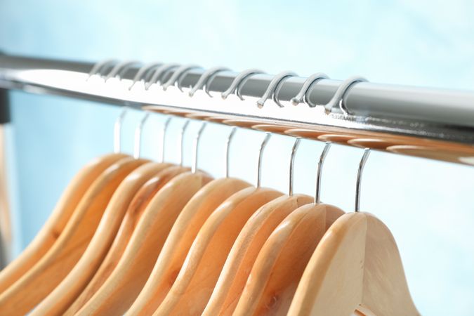 Hangers on rod against blue background, close up