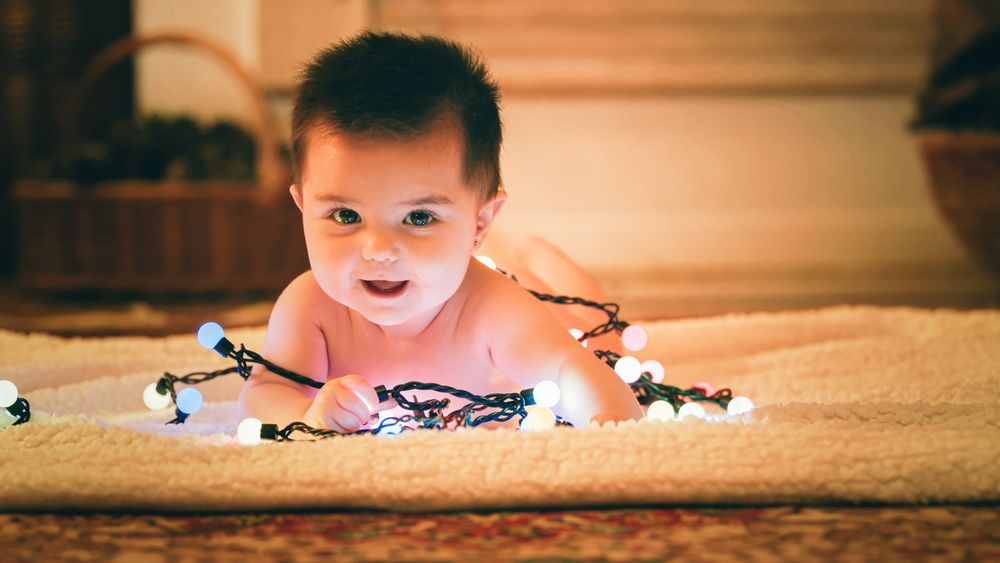 Baby playing with light garland on Christmas Day