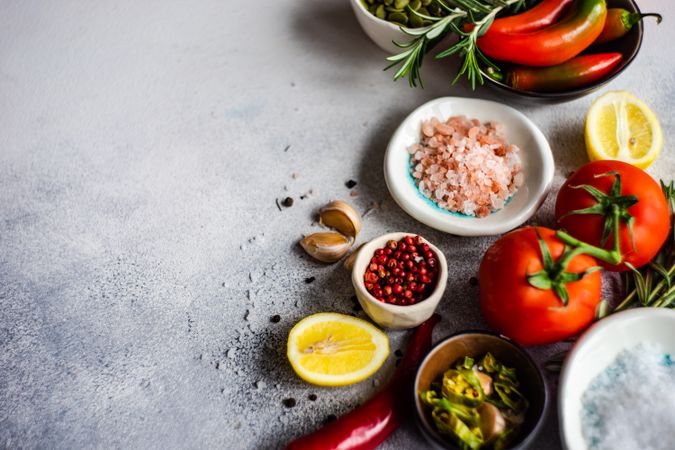 Tomatoes, Himalayan salt, red peppercorns, lemon, garlic & herbs on counter with copy space