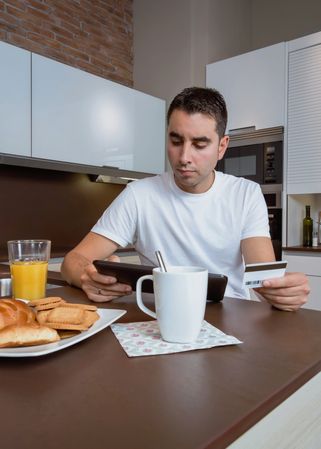 Man paying for something with credit card and digital tablet over breakfast