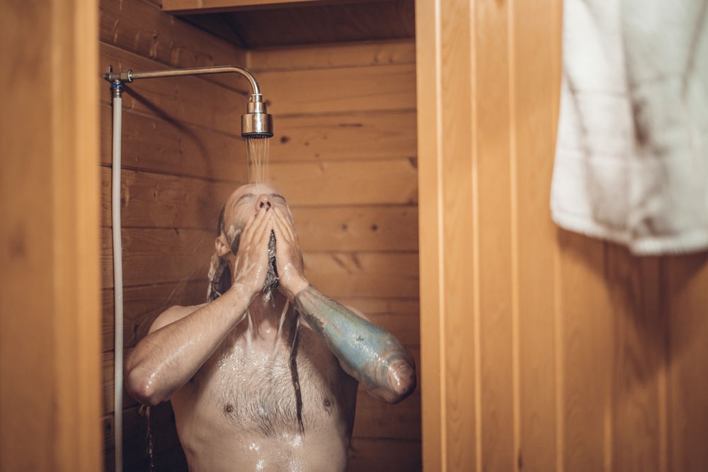 Man taking shower in wooden bathroom