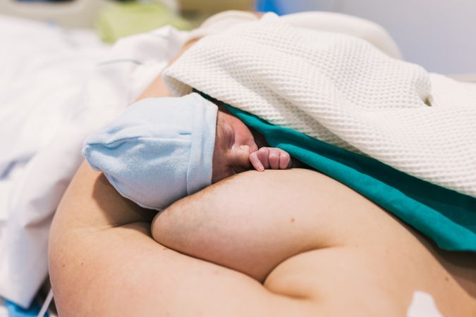 Woman holding her newborn baby after giving birth in hospital room.