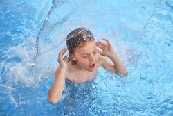 Boy with opened mouth and closed eyes in swimming pool