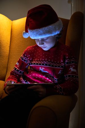 Child in Santa Claus hat using tablet